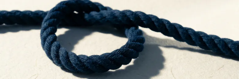 Ujung tali navy yang terbuka membentuk satu lingkaran yang belum diikat di atas kertas cream